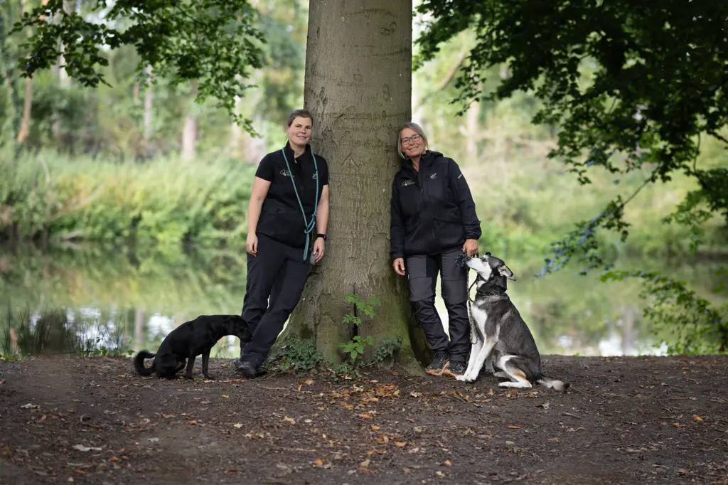 Hundeschule Münster – Trainerinnen Britta und Tamara mit Hunden auf dem Trainingsplatz der Hundeschule NordWestPfoten